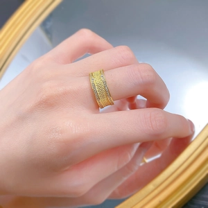 Détail d'une bague large dorée style vintage avec texture tressée et zircons sertis