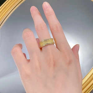 Détail d'une bague large dorée avec texture tressée et sertissage de zircons cubiques