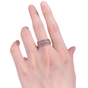 Vintage rose gold lace ring with red and white gemstones worn on hand on white background
