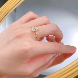 Macro view of pear cut white zircon set in gold plated silver band on finger
