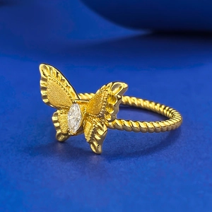Macro shot of gold ribbon ring with twisted band and marquise gemstone on blue background