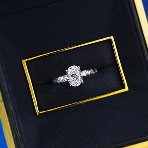 Detailed macro view of an oval cut gemstone ring with baguette side diamonds in a blue box