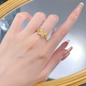 Macro detail of a golden butterfly ring with brushed wings and a sparkling zircon stone