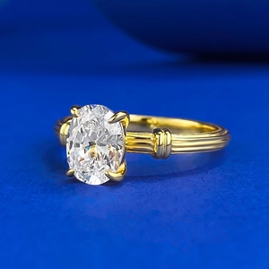 S925 silver gold plated ring with oval clear zircon and textured band on blue background