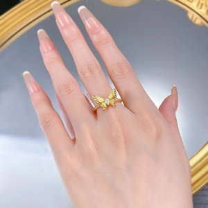 Detail of gold butterfly ring with brushed wings and twisted band worn on finger