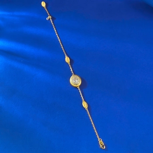 Détail du bracelet doré avec breloque ovale en cristal sur fond bleu texturé élégant