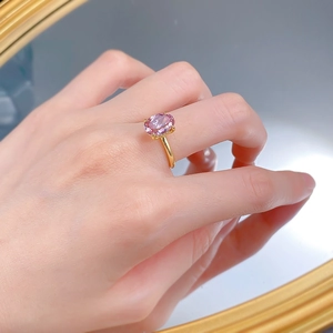 Gros plan d'une bague dorée avec diamant rose ovale portée par un mannequin