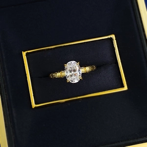 Macro shot of oval-cut solitaire stone with ribbed gold band in a blue velvet box