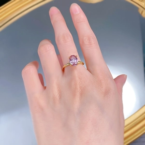 Gros plan d'une bague en argent S925 plaqué or avec diamant rose ovale portée au doigt