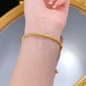 Gros plan du bracelet tissé doré montrant la texture en maille et le fermoir de sécurité