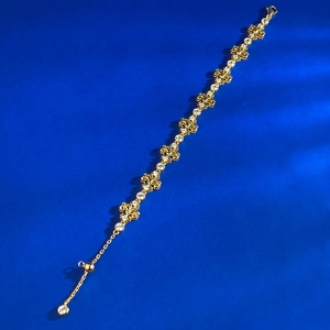 Detail of iris gold bracelet with zircon inlays and adjustable slider on blue background