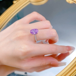 Macro detail of oval cut purple gemstone ring with diamond pavé setting on hand