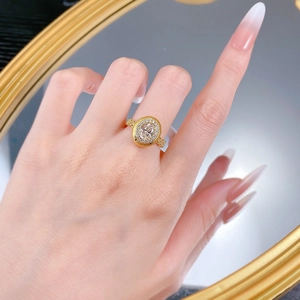 Détail macro d'une bague dorée brossée vintage avec cristal ovale portée au doigt