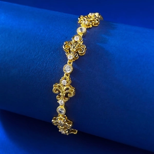 Close-up of vintage fleur-de-lis gold bracelet with white zircons on blue stand