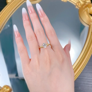 Detailed view of an oval-cut solitaire gold ring on a finger with starburst settings