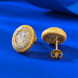 Vue détaillée de boucles d'oreilles ovales dorées avec zircone et texture brossée