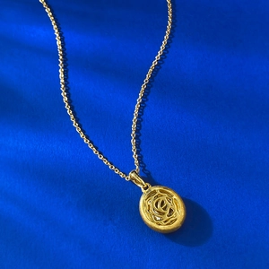 Macro detail of S925 silver gold-plated oval pendant with hollow rose floral pattern