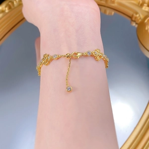 Detailed view of an adjustable gold iris flower bracelet with zircons on a wrist