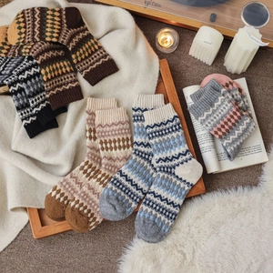 Flat lay of Nordic Fair Isle knit wool socks in various colors on a cozy home setting