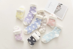Detailed view of colorful coral fleece socks with white heart patterns and plush cuffs