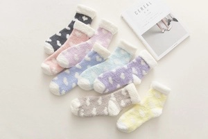 Close-up of pastel coral fleece socks with heart patterns and thick white cuffs