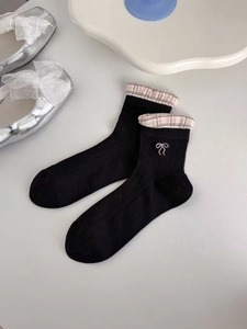 Detail of black mesh socks with pink plaid cuff and white bow embroidery decoration