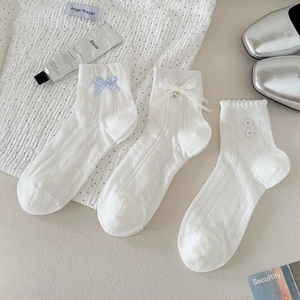 Trois paires de chaussettes blanches en dentelle avec nœuds et détails de boutons