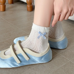 Détails de chaussettes en dentelle blanche avec motifs cœurs et nœuds bleus sur le côté