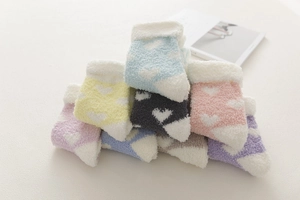 Close-up of thick coral fleece winter socks with heart patterns in vibrant candy colors