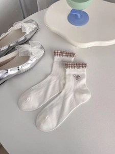 Detail of white crew socks with bow embroidery and silver shoes with organza ribbon
