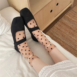 Detailed view of sheer skin-tone socks with black heart patterns and Mary Jane shoes
