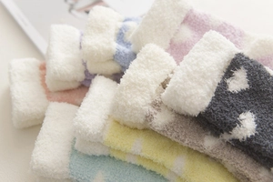 Close-up of colorful coral fleece socks with heart patterns and thick white folded cuffs