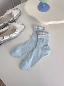 Close-up of light blue mesh socks with bow embroidery and blue-white plaid cuffs