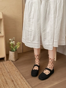 Detail of sheer heart pattern socks paired with black split-toe Mary Jane shoes