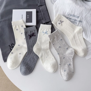 Detail of five assorted cotton socks featuring bow knots, floral patterns, and ribbed texture