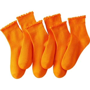 Detail of six pairs of vibrant orange crew socks with elegant ruffle cuffs and ribbed texture