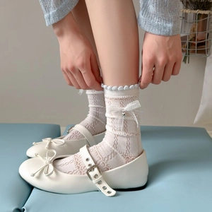 Detail of white lace Lolita socks with bow and bell paired with Mary Jane shoes