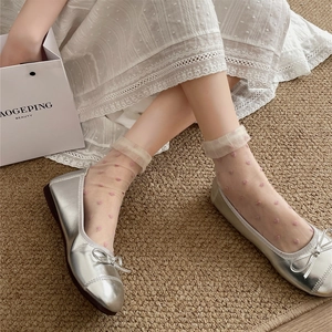 Close-up of sheer mesh crew socks featuring pink heart pattern with silver ballet flats