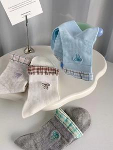 Close-up of pastel mesh socks with delicate bow embroidery and plaid cuff details