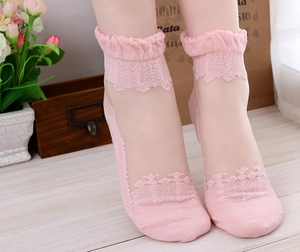 Close-up of pink lace sheer socks with ruffle cuffs on a rustic wooden background