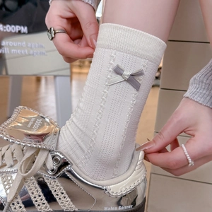 Close-up of off-white ribbed knit socks with side bow detail and vintage texture