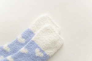 Close-up of thick light blue coral fleece socks with white heart patterns and soft texture