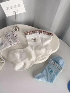Detail of sheer mesh crew socks with bow embroidery and plaid cuffs in cream and blue