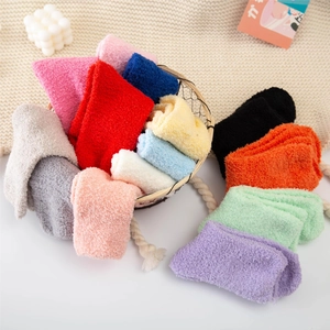 Detail of colorful coral fleece socks in a bamboo basket with a cozy knit background