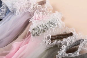 Close-up of delicate lace embroidery and sheer mesh texture on stylish crystal socks