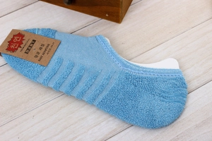 Close-up of sky blue low-cut cotton socks with terry sole and adaptive hangtag