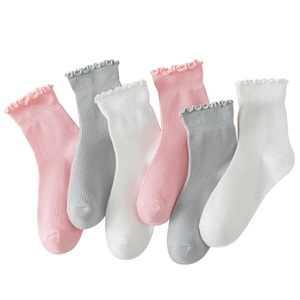 Close-up of ruffled cuff knit socks in pink, white, and gray with ribbed cotton texture