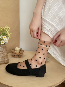 Detail of sheer mesh crew socks with black heart pattern worn with Mary Jane shoes