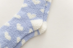 Detail of light blue coral fleece sock with white heart pattern and soft plush texture