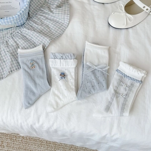 Detailed close-up of light blue and white mesh socks with lace trim and bear embroidery